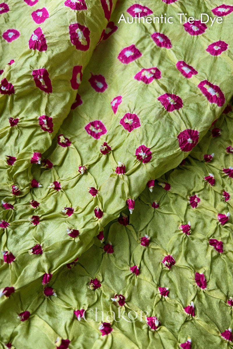 Close-up of Pista Green mulberry silk fabric with Pink and white patterns, featuring texture of authentic bandhani patterns.
