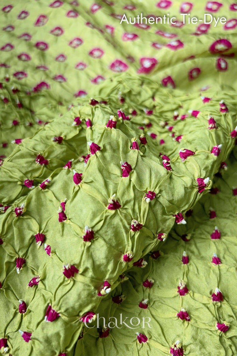 Close-up of Pista Green mulberry silk fabric with Pink and white patterns, featuring texture of authentic bandhani patterns.
