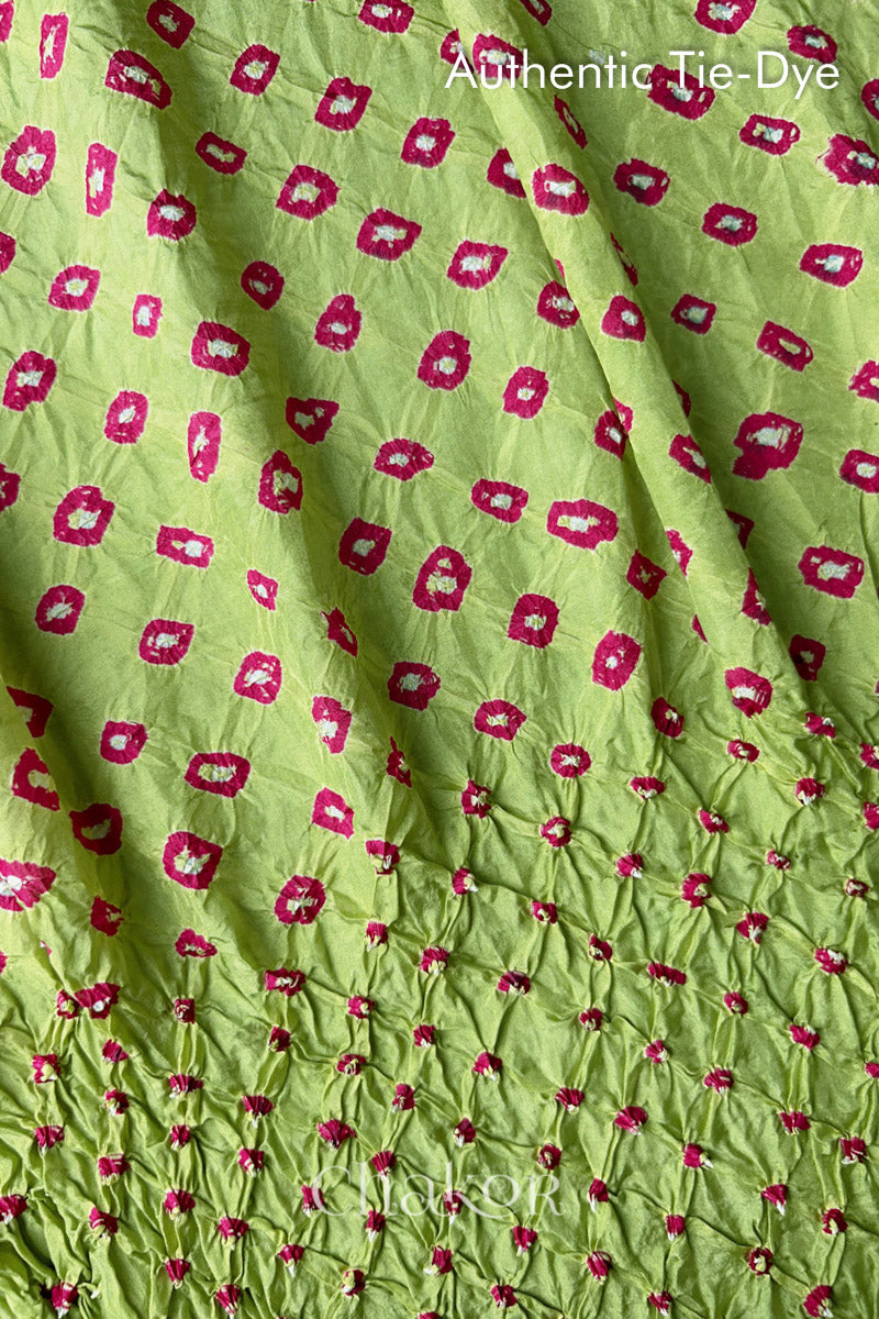 Close-up of Pista Green mulberry silk fabric with Pink and white patterns, featuring texture of authentic bandhani patterns.
