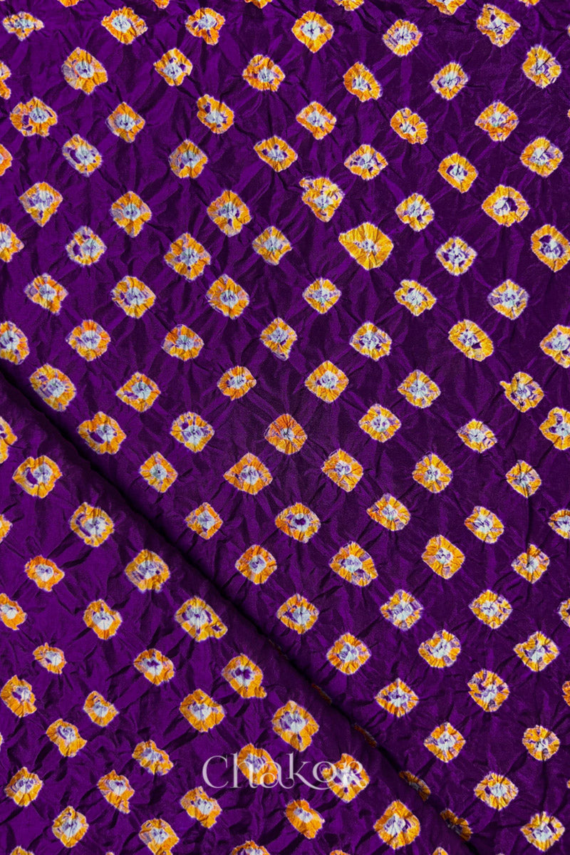 Purple Mulberry silk fabric showcasing dual colour Yellow bandhani patterns with folded corner and Chakor brand watermark.
