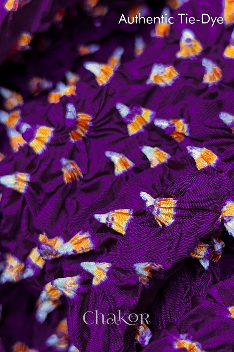 Close-up of Purple mulberry silk fabric with Yellow and white patterns, featuring texture of authentic bandhani patterns.

