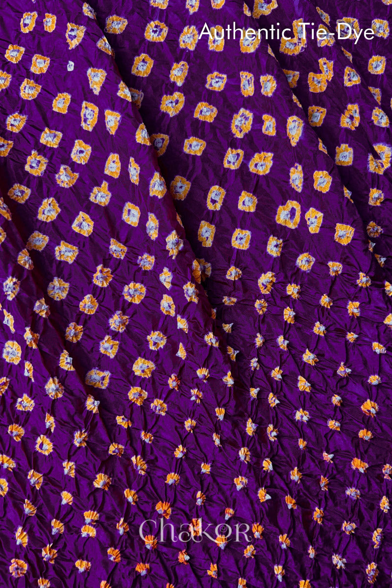 Close-up of Purple mulberry silk fabric with Yellow and white patterns, featuring texture of authentic bandhani patterns.
