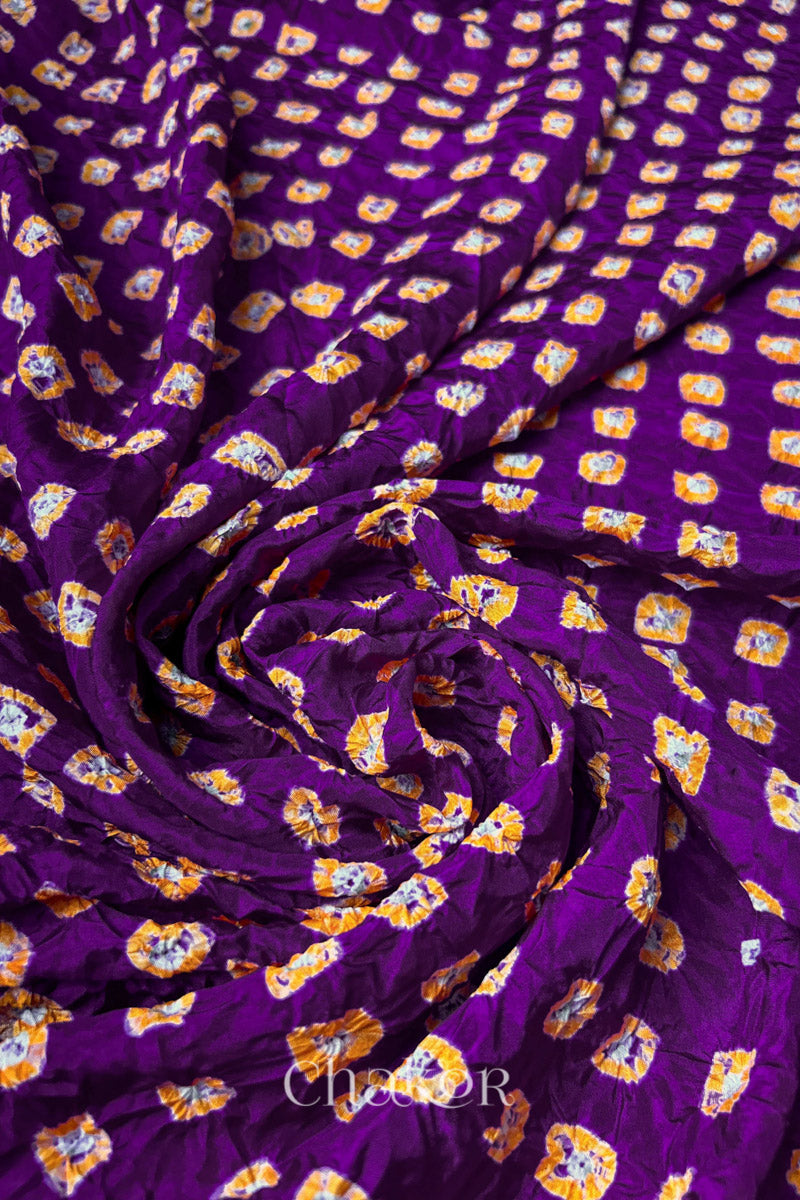 Purple Mulberry silk fabric with dual colour Yellow bandhani dots, arranged in a swirling design  & Chakor brand watermark.
