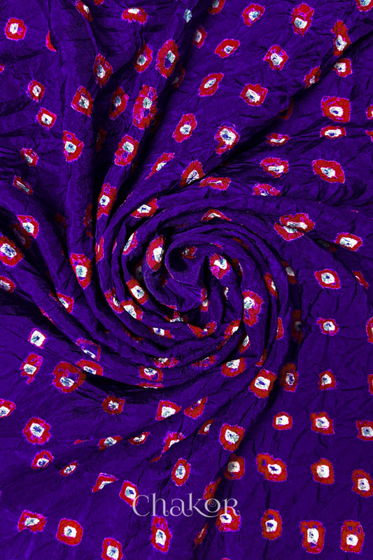 Purple Mulberry silk fabric with dual colour Red bandhani dots, arranged in a swirling design  & Chakor brand watermark.
