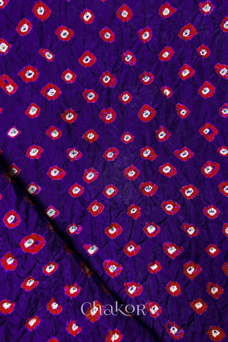Purple Mulberry silk fabric showcasing dual colour Red bandhani patterns with folded corner and Chakor brand watermark.
