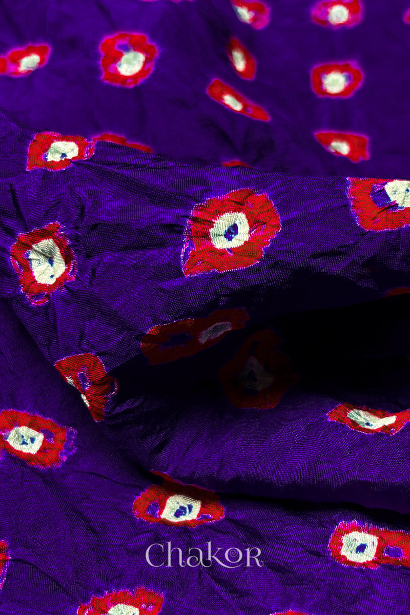 Close-up of Purple fabric with Red and white bandhani patterns, featuring texture and sheen of soft mulberry silk fabric.
