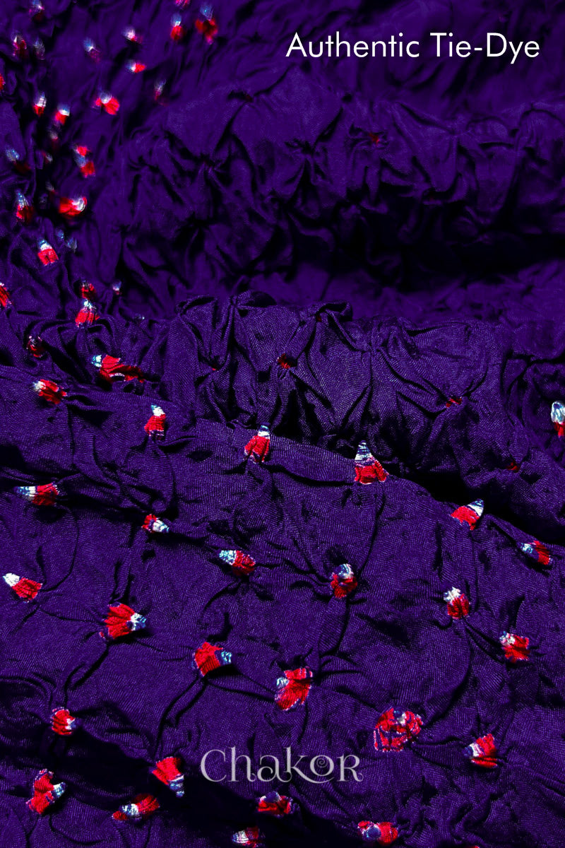 Close-up of Purple mulberry silk fabric with Red and white patterns, featuring texture of authentic bandhani patterns.
