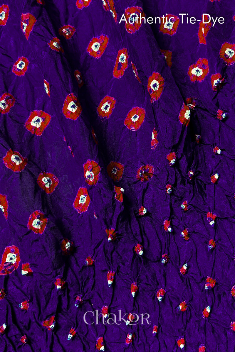 Close-up of Purple mulberry silk fabric with Red and white patterns, featuring texture of authentic bandhani patterns.
