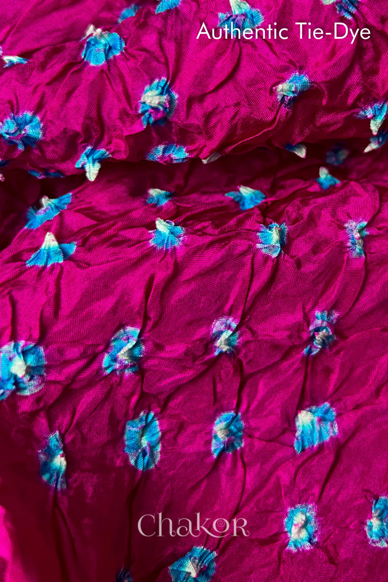 Close-up of Rani Pink mulberry silk fabric with Turquoise Blue and white patterns, featuring texture of authentic bandhani patterns.
