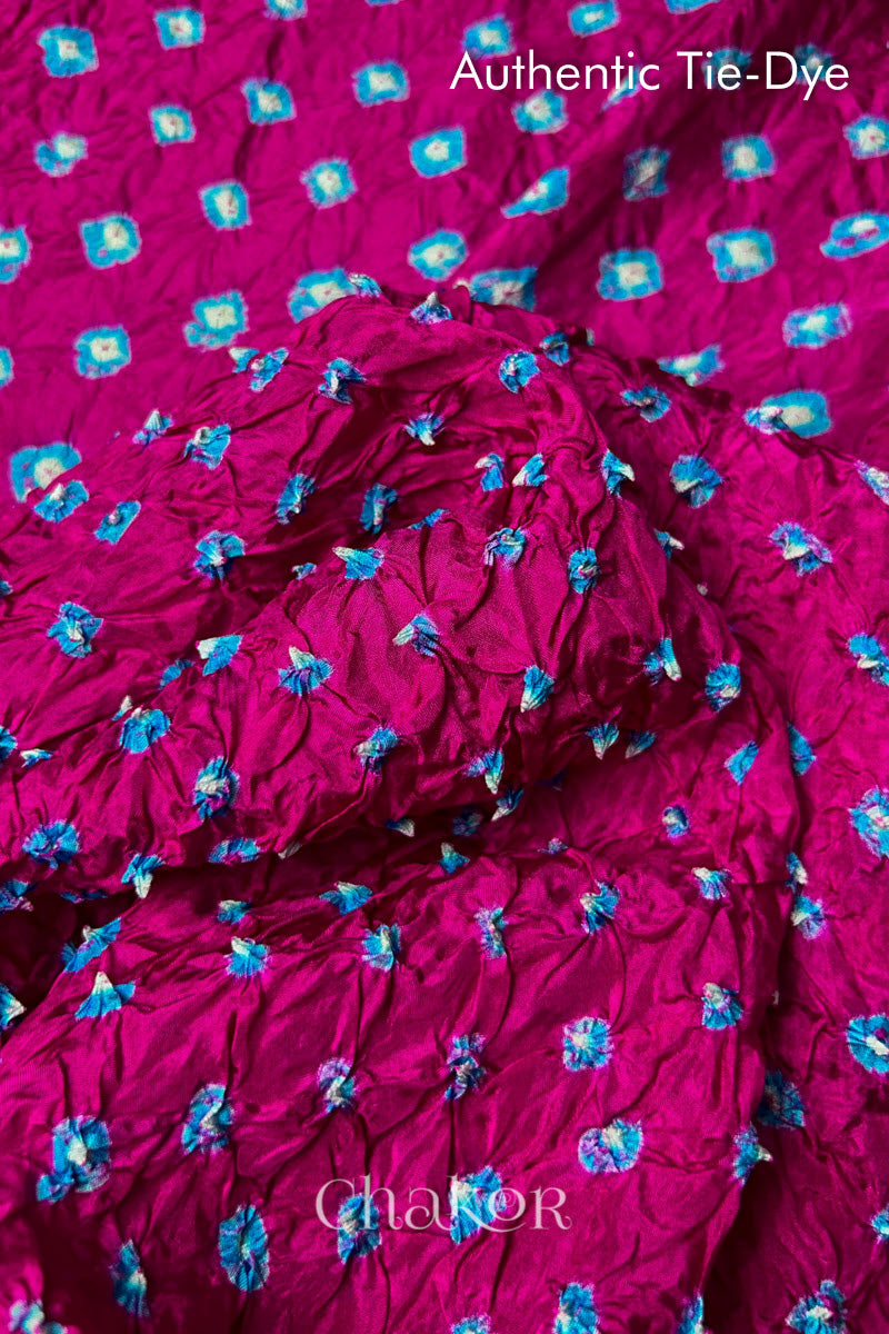 Close-up of Rani Pink mulberry silk fabric with Turquoise Blue and white patterns, featuring texture of authentic bandhani patterns.
