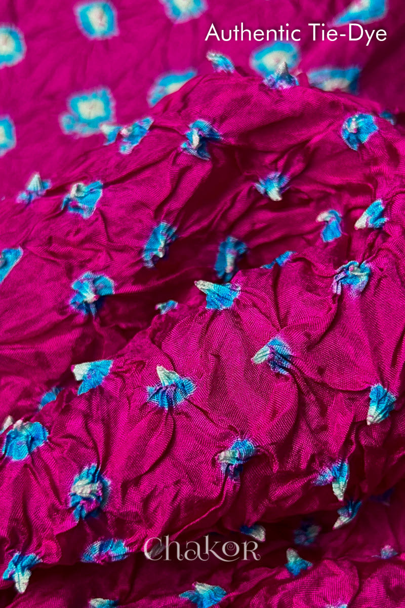 Close-up of Rani Pink mulberry silk fabric with Turquoise Blue and white patterns, featuring texture of authentic bandhani patterns.

