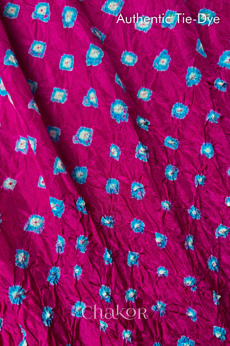 Close-up of Rani Pink mulberry silk fabric with Turquoise Blue and white patterns, featuring texture of authentic bandhani patterns.
