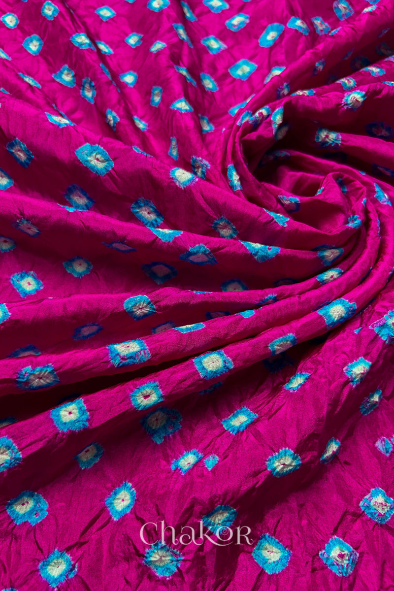 Rani Pink Mulberry silk fabric with dual colour Turquoise Blue bandhani dots, arranged in a swirling design  & Chakor brand watermark.
