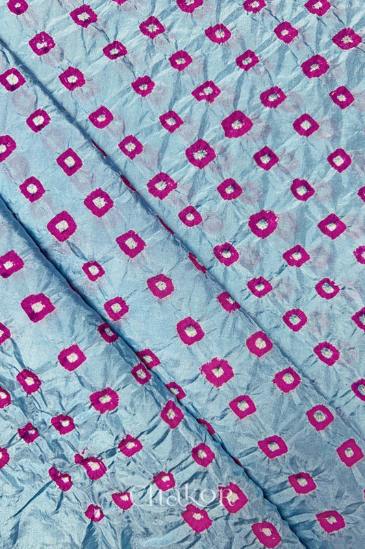 Sky Blue Mulberry silk fabric showcasing dual colour Pink bandhani patterns with folds and Chakor brand watermark.
