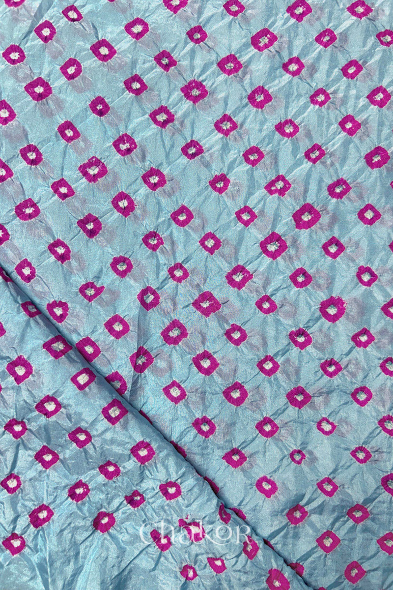 Sky Blue Mulberry silk fabric showcasing dual colour Pink bandhani patterns with folded corner and Chakor brand watermark.
