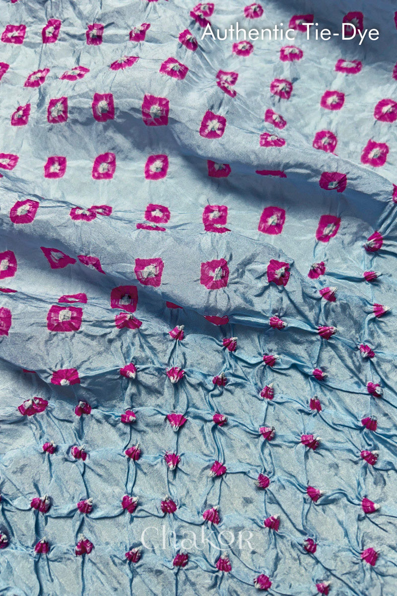 Close-up of Sky Blue mulberry silk fabric with Pink and white patterns, featuring texture of authentic bandhani patterns.
