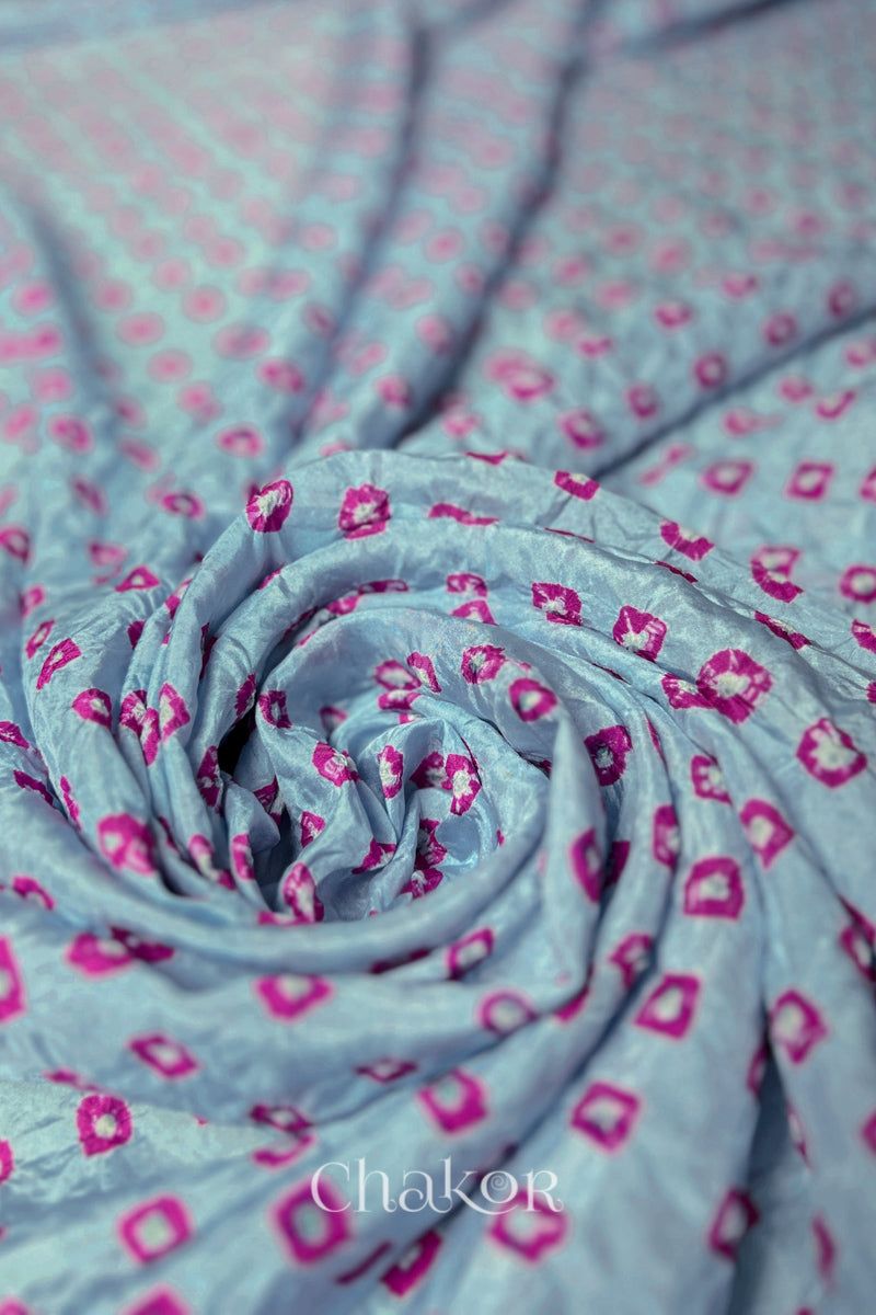 Sky Blue Mulberry silk fabric with dual colour Pink bandhani dots, arranged in a swirling design  & Chakor brand watermark.
