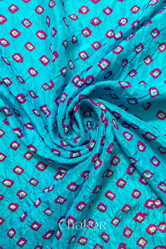 Turquoise Blue Mulberry silk fabric with dual colour Pink bandhani dots, arranged in a swirling design  & Chakor brand watermark.
