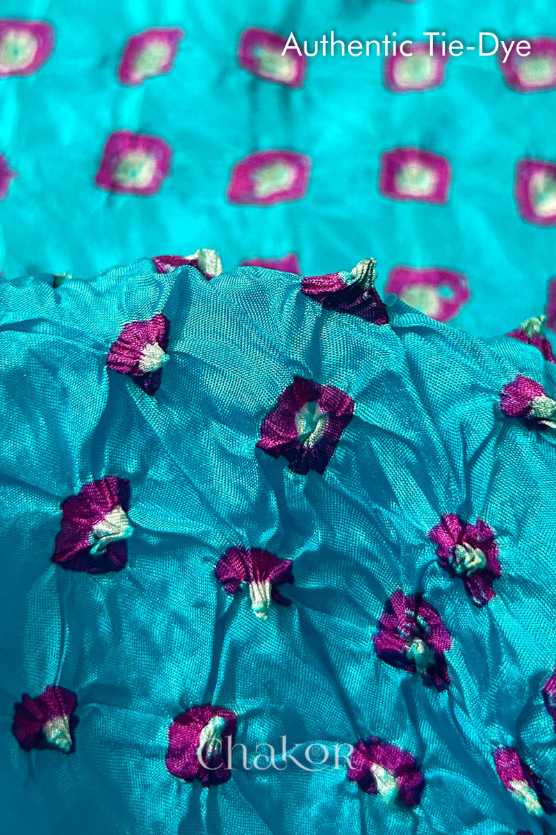 Close-up of Turquoise Blue mulberry silk fabric with Pink and white patterns, featuring texture of authentic bandhani patterns.
