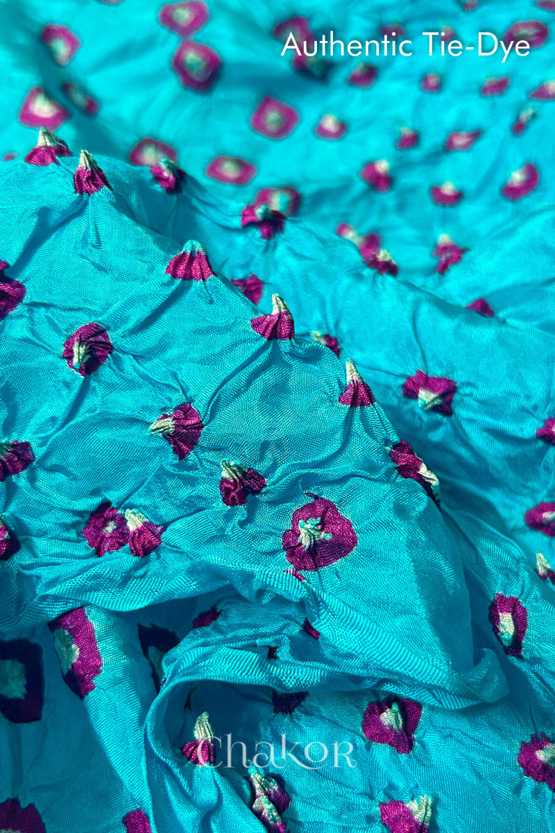 Close-up of Turquoise Blue mulberry silk fabric with Pink and white patterns, featuring texture of authentic bandhani patterns.
