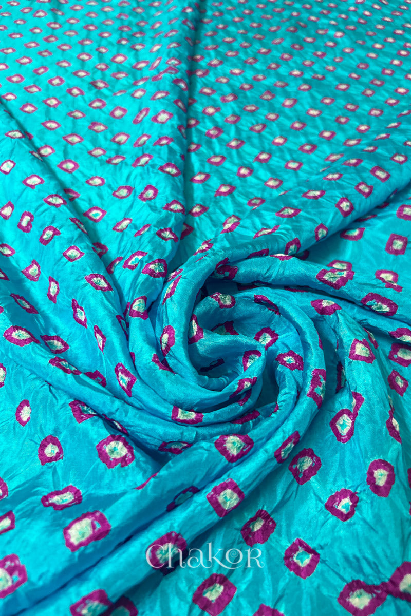 Turquoise Blue Mulberry silk fabric with dual colour Pink bandhani dots, arranged in a swirling design  & Chakor brand watermark.
