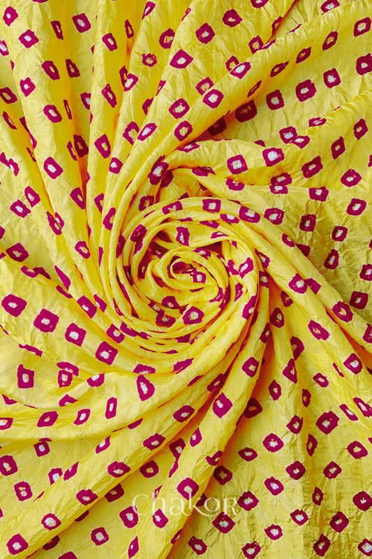 Yellow Pink Mulberry silk fabric with dual colour Pink bandhani dots, arranged in a swirling design  & Chakor brand watermark.
