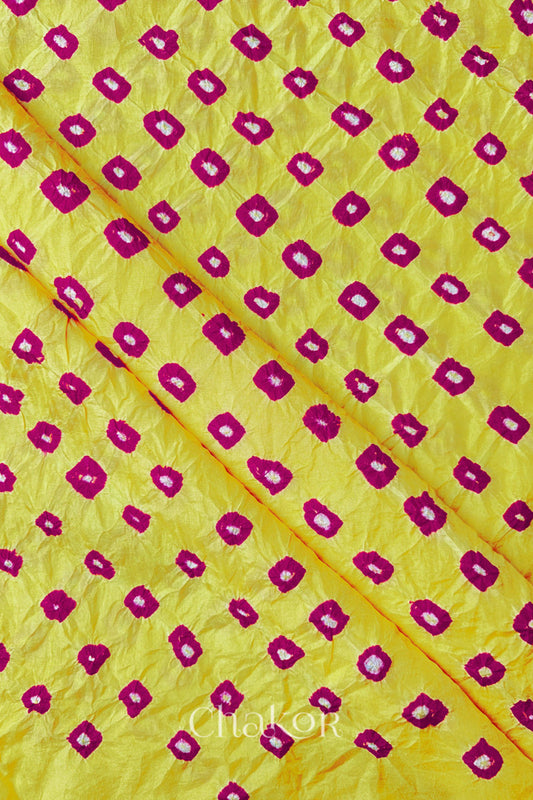 Yellow Pink Mulberry silk fabric showcasing dual colour Pink bandhani patterns with folds and Chakor brand watermark.
