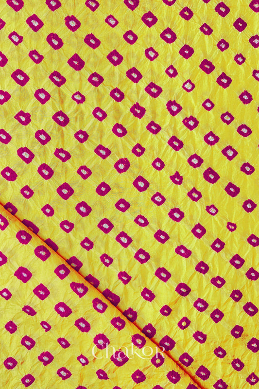 Yellow Pink Mulberry silk fabric showcasing dual colour Pink bandhani patterns with folded corner and Chakor brand watermark.
