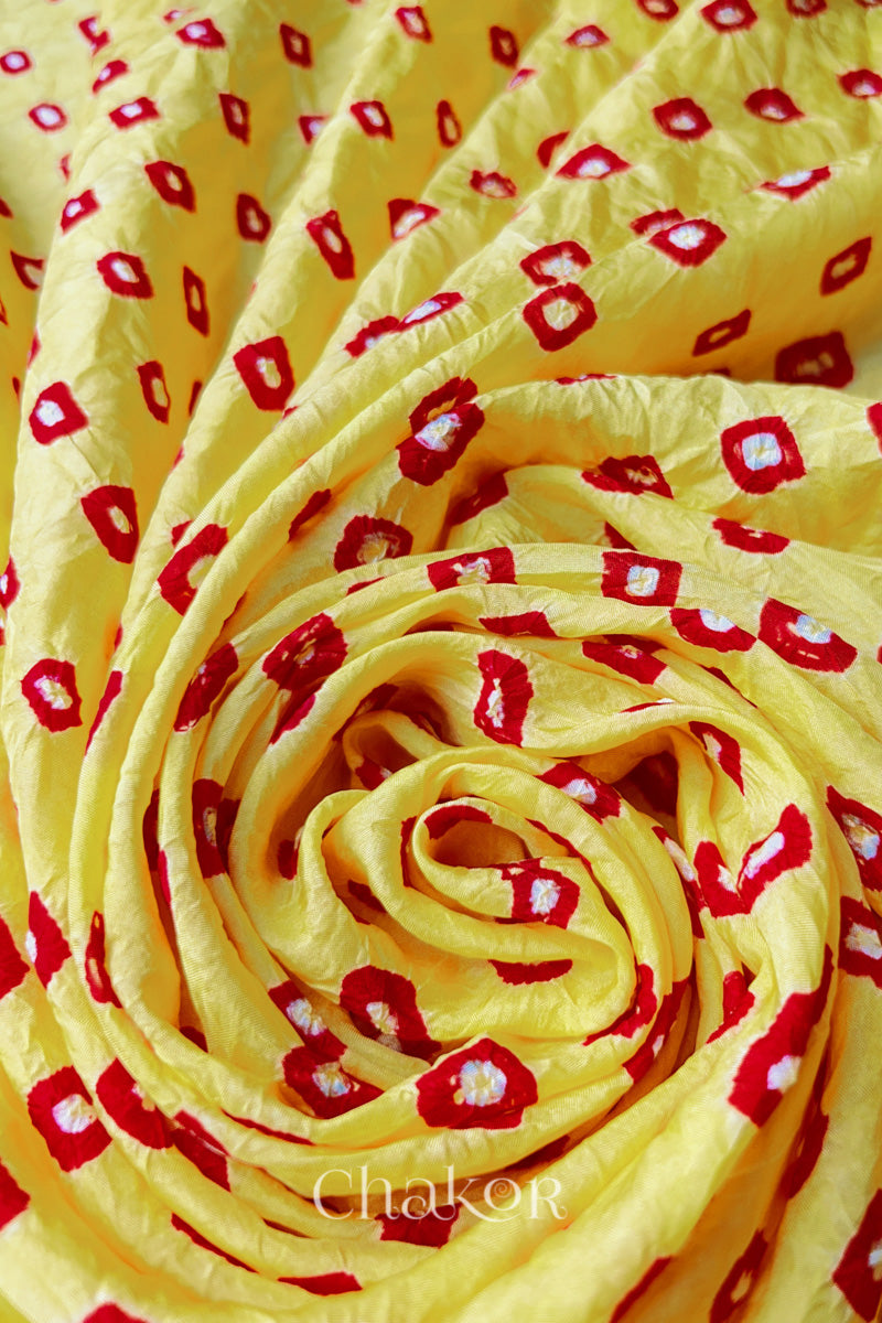 Yellow Red Mulberry silk fabric with dual coloured bandhani dots, arranged in a swirling design  & Chakor brand watermark.