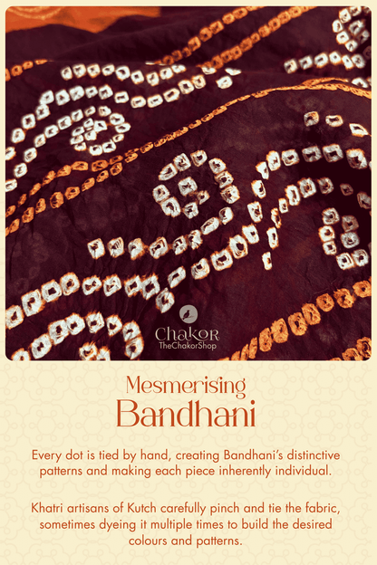 Close-up of dark maroon cotton Bandhani with orange and white hand-tied motifs, illustrating the intricate tying technique of Kutch Bandhani.