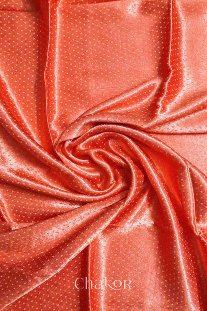 Close up of Handcrafted Peach Mashru Blouse Fabric with self woven design and silky texture.