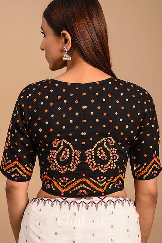 A woman wearing a traditional Black Bandhani Cotton Blouse with intricate mirror embroidered Keri - Paisley motifs and boria fabric buttons.